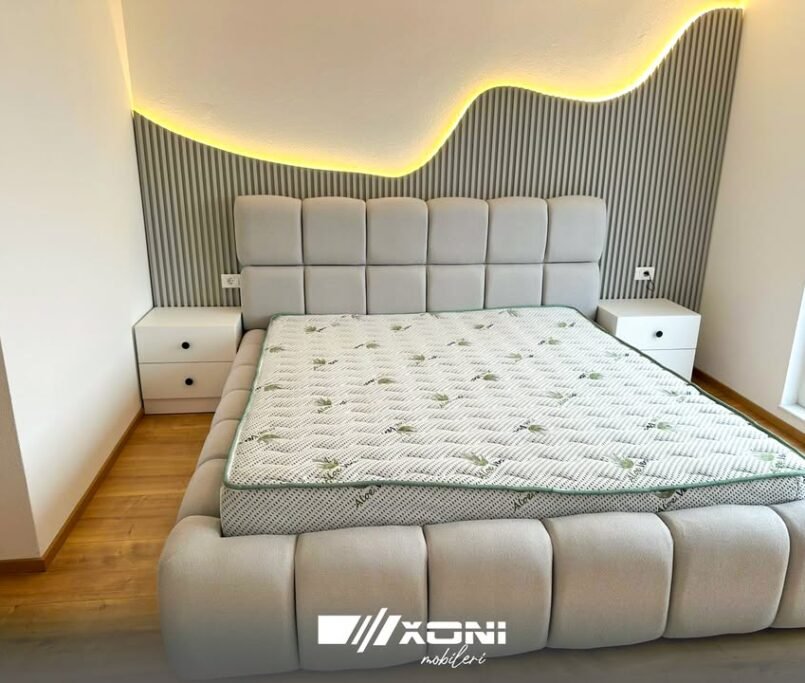 Dhomë gjumi moderne me krevat beige dhe komodina të bardha në Ferizaj