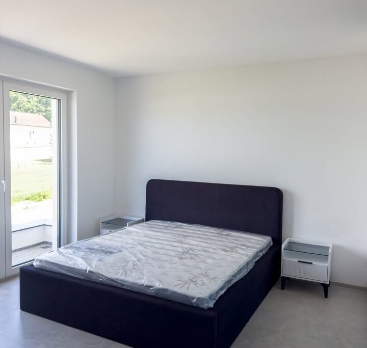 Dhomë gjumi moderne me krevat beige dhe komodina të bardha në Ferizaj