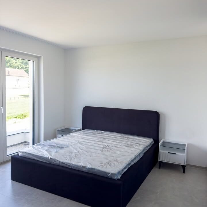 Dhomë gjumi moderne me krevat beige dhe komodina të bardha në Ferizaj