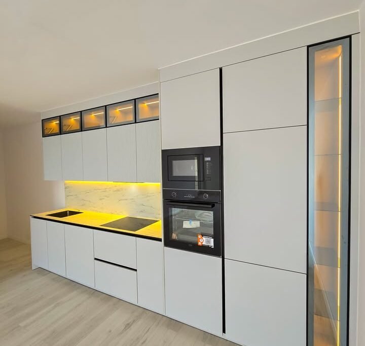 Pamje e kuzhinës moderne me sipërfaqe të lëmuara dhe ndriçim LED, stil funksional